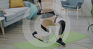 Slow motion of elderly woman with elastic resistance band doing sports indoors in apartment