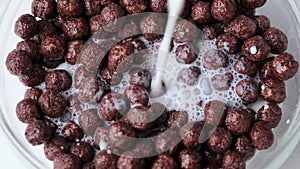 Slow motion falling chocolate cereal balls with milk.