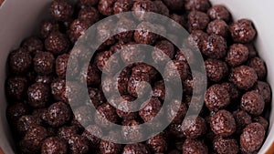 Slow motion falling chocolate cereal balls top view.