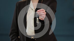 Slow motion of female`s midsection in formal jacket holding house keys in hand and showing to camera. Real-estate agent