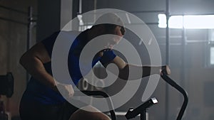 Slow motion: fitness man on bicycle doing spinning at gym. Fit young male working out on gym bike