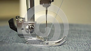 Slow motion of the foot and needle while sewing on the sewing machine.Close-up.