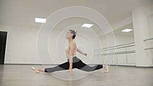 Slow motion footage of flexible woman ballet dancer doing wheel jump combining with longitudinal split sitting in dance