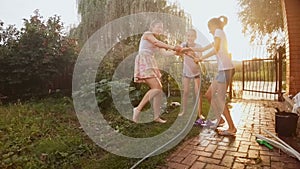 Slow motion footage of happy cheerful family splashing water from hose pipe at garden