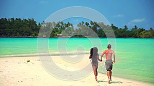 Slow motion footage: interracial happy couple enjoy honeymoon on the tropical beach at sunny summer day.