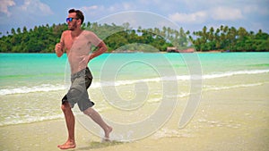 Slow motion footage: Man runs along tropical beach