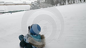Slow motion footage of a young boy sledging down and jumping up on trampoline at a snow-covered hill