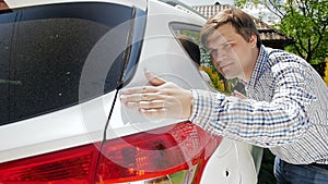 Slow motion footage of young man looking closely at his new car