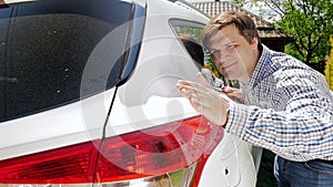 Slow motion footage of young smiling man touching gently his car