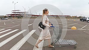 Slow motion footage of young woman walking to the supermarket on parking lot