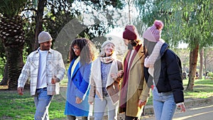 Slow motion fotage of a group of international best friends walking and talking at downtown park, smiling and laughing