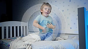 Slow motion of funny smiling toddler boy having fun and dancing before going to sleep. Sleepless little boy refuses to