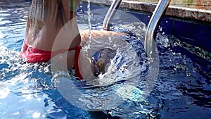 Slow motion of girl climbing out of swimming pool