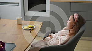 Slow motion. The girl has lost her appetite as she cuts a pancake with a dessert knife while sitting indoors in a