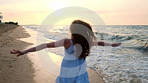 SLOW MOTION: Girl running in shallow water at sunset. A girl in a white dress is running at the water`s edge near the