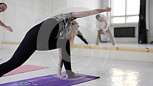 Slow motion Group of people practicing yoga, standing in Extended Side Angle yoga pose