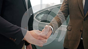 Slow motion of handshake, male customer buying car in showroom taking keys