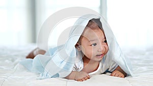 Slow-motion of happy baby lying on bed under blanket in bedroom