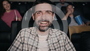 Slow motion of happy bearded man laughing watching film in dark cinema
