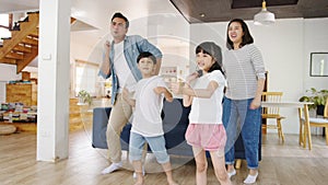 Slow motion - Happy cheerful Asian family having fun listen to music and dancing in living room at modern home. Spending time