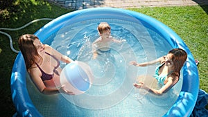 Slow motion of happy cheerful family having fun with inflatable beach ball in outdoor swimming pool. Concept of happy