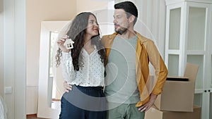 Slow motion of happy couple holding house key smiling standing indoors in beautiful room