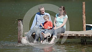 Slow motion happy family on pontoon hit the water with their feet
