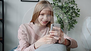 Slow motion of happy kid using smart phone at home smiling swiping enjoying internet content