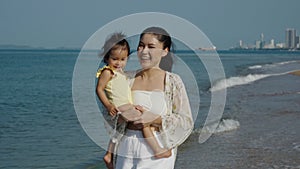 slow motion of happy mother holding and running with her toddler baby girl on sea beach