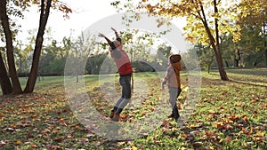 Slow motion. Happy mother and son playing in autumn Park with yellow leaves.