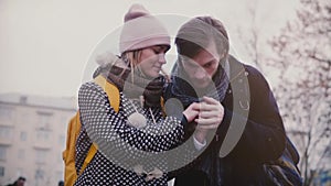 Slow motion happy smiling young European man and woman walk together having fun on a date on a cold snowy winter day.