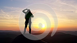 Slow motion of happy woman climber dancing on top of mountain at sunset