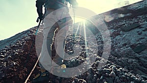 Slow motion of hiker man hiking on the rocks in the mountains in a cold day in spring or summer. Backlit sun light at