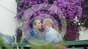 Slow motion of homosexual men kissing on bench in summer park