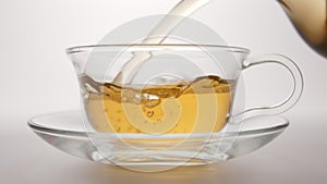 SLOW MOTION: Hot tea flowing to a tea cup from a teapot - close up