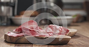 Slow motion of Italian coppa ham falling on wood board closeup