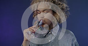 Slow motion of joyful African American girl dancing with champagne glass partying on blue color background