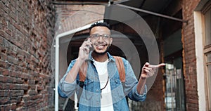 Slow motion of joyful African American guy talking on mobile phone outdoors