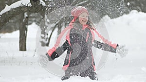 Slow motion of joyful child playing in snow. Happy girl having fun outside winter day