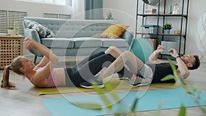Slow motion of joyful couple man and woman doing sit-ups training at home together