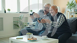 Slow motion of joyful friends senior men playing video game then doing high-five