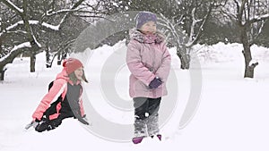 Slow motion of joyful kids playing in snow. Two happy girls having fun outside winter day