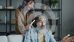 Slow motion of joyful mature man expressing positive emotions looking at pregnancy test and happy wife