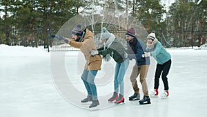 Slow motion of joyful young people ice-skating in park together laughing having fun