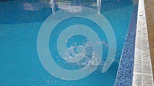 Slow motion jump into a swimming pool. Boy jumping into the water.