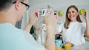 Slow motion of lady posing with apples when guy taking photo with smartphone