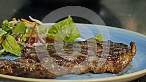 Slow motion of a large beef sirloin steak served on a plate