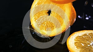 Slow motion of lemons falling with water drops on black surface.