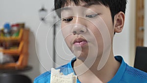 Slow motion of Little asian schoolboy eating sandwich,