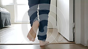 Slow motion of little boy's energetic feet as he runs along the long wooden corridor in his home.